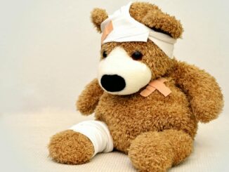 A brown teddy bear with bandages, depicting a playful take on injury recovery in a minimalist setting.