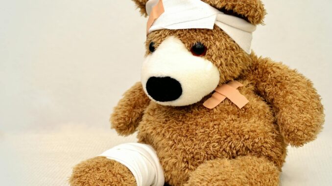 A brown teddy bear with bandages, depicting a playful take on injury recovery in a minimalist setting.